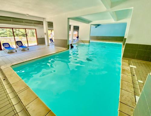 a swimming pool with blue water in a building at Appartement sur les pistes de ski avec piscine in Sainte-Marie-de-Vars