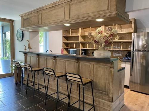 a kitchen with a bar with chairs and a refrigerator at La Héronnière - gîte de groupe in Houlle