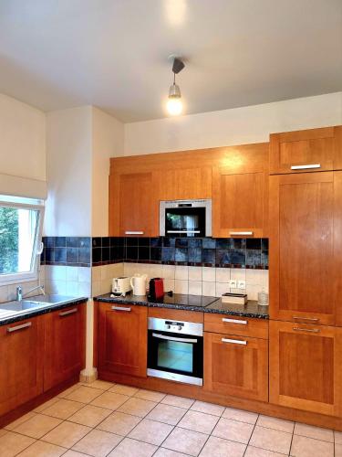 a kitchen with wooden cabinets and a stove top oven at Appartement front populaire stade de france in Saint-Denis