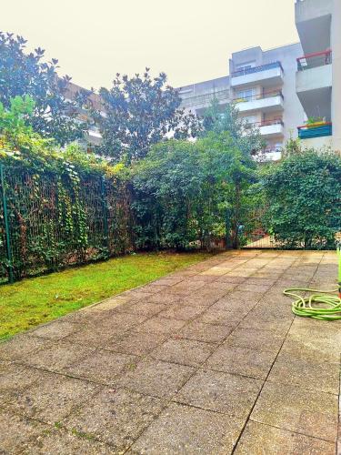 a garden with a fence and a bench on a sidewalk at Appartement front populaire stade de france in Saint-Denis