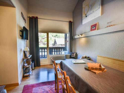 une salle à manger avec une table et des chaises et une fenêtre dans l'établissement Charmant T2 avec mezzanine près des pistes et du centre des Gets - 5 pers., balcon, parking, wifi - FR-1-685-72, aux Gets