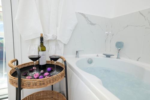 a bath tub with two glasses of wine and a basket with wine glasses at 3bd jacuzzi mansion in Athens