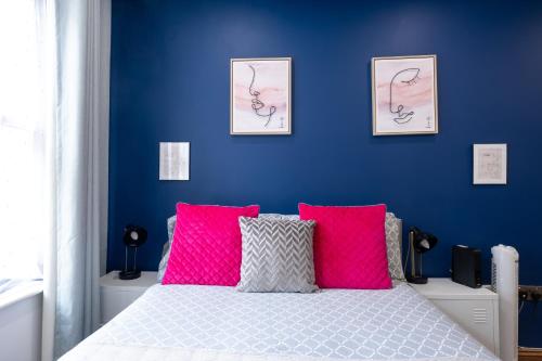 Schlafzimmer mit blauen Wänden und einem Bett mit rosa Kissen in der Unterkunft REEF9 - Modern central flat, 5 mins from beach, centre and Bournemouth International Centre in Bournemouth