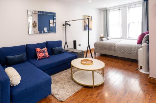 ein Wohnzimmer mit einem blauen Sofa und einem Bett in der Unterkunft REEF9 - Modern central flat, 5 mins from beach, centre and Bournemouth International Centre in Bournemouth