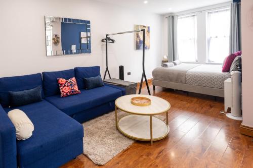 a living room with a blue couch and a bed at REEF9 - Modern central flat, 5 mins from beach, centre and Bournemouth International Centre in Bournemouth