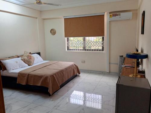 um quarto com uma cama grande e uma janela em Edgard Hotel em Accra