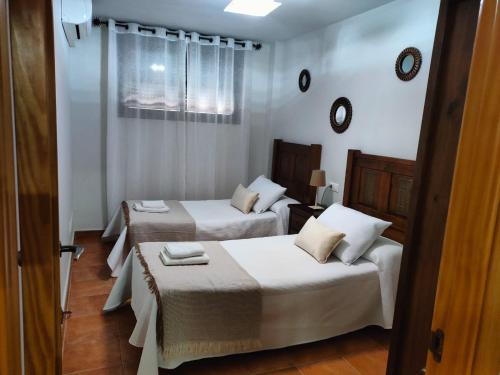 2 camas en una habitación con paredes blancas en VFT Castillo de la Yedra, en Cazorla