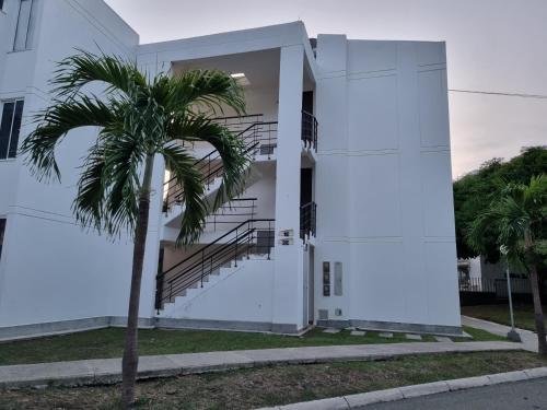 a white building with a palm tree in front of it at Apartasol Ciudadela Santafe in Santa Fe de Antioquia