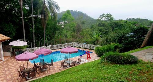 una piscina con tavoli, sedie e ombrelloni di Casarão perto SP e Rodeio Cajamar - Piscina, Hidro e Lareira com Brinquedos em condomínio de Luxo a Cajamar