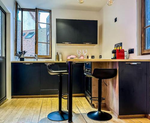 a kitchen with a bar with two stools at a counter at Flamant Rose in Annecy