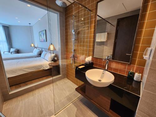 a bathroom with a sink and a bed and a mirror at Apec Mandala Wyndham Mui Ne - V Ruby in Ấp Thiẹn Ái