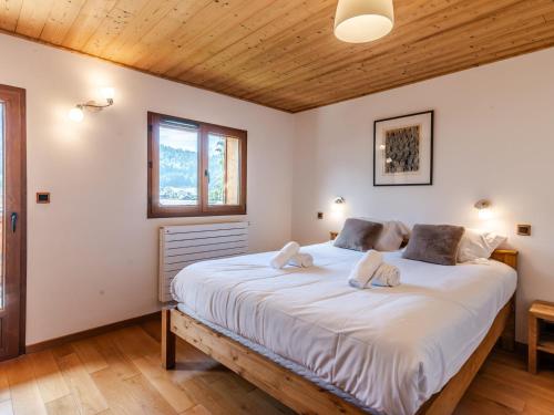 ein Schlafzimmer mit einem großen weißen Bett mit zwei Kissen in der Unterkunft Chalet rénové 4* avec cheminée et animaux admis - FR-1-754-32 in Morzine