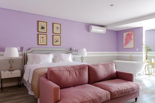 a bedroom with a bed and a couch and a tub at Villa do Vale Boutique Hotel in Blumenau
