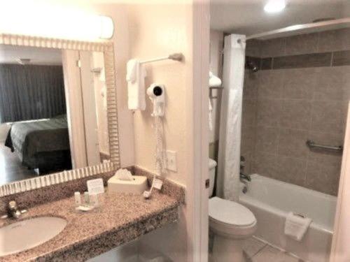 La salle de bains est pourvue d'un lavabo, de toilettes et d'un miroir. dans l'établissement Quality Inn Hinesville - Fort Stewart Area, Kitchenette Rooms - Pool - Guest Laundry, à Hinesville
