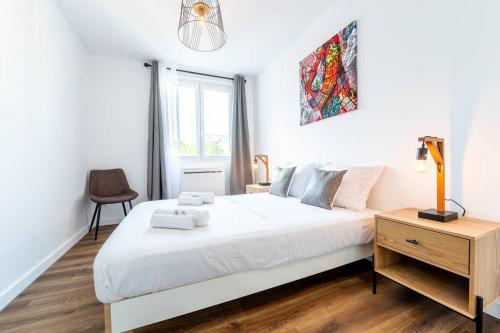 una camera con un grande letto bianco e una sedia di Esprit Marvel: 2 chambres- fibre- balcon- parking a Grenoble