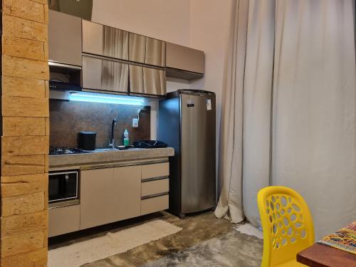 uma cozinha com um frigorífico de aço inoxidável e uma cadeira amarela em Vila Manguezal, 2 suítes com opção de piscina e sauna integrada privativas na rota ecológica dos Milagres em Pôrto de Pedras