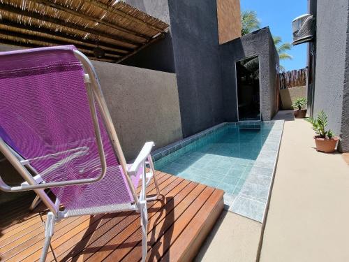 a chair sitting on a deck next to a swimming pool at Vila Manguezal, 2 suítes com opção de piscina e sauna integrada privativas na rota ecológica dos Milagres in Pôrto de Pedras