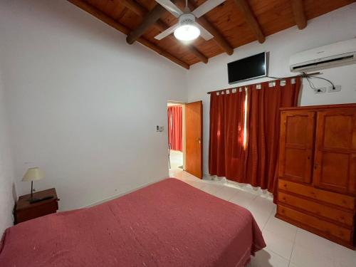 1 dormitorio con cama roja y TV en la pared en Complejo El Ensueño, en Colón