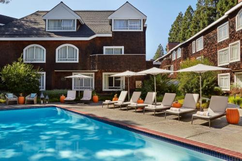 a swimming pool with lounge chairs and umbrellas at The Stanford Park Hotel in Menlo Park