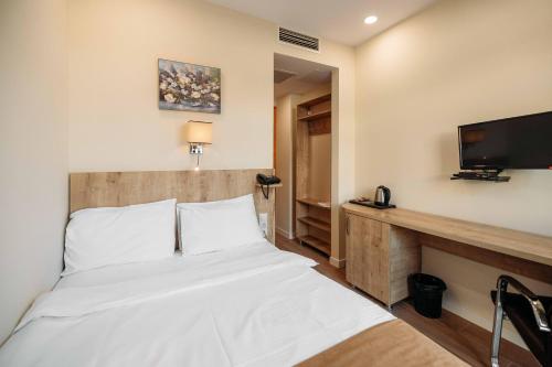 a bedroom with a bed and a flat screen tv at Atrium Boutique Hotel in Tbilisi City