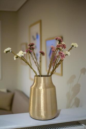 a gold vase with flowers in it on a table at House Apartment Anna Maria in Tríkala