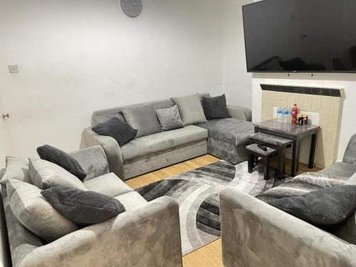 Hometel Large Luxurious Comfy Home Can Sleep 16 في Thornton Heath: غرفة معيشة مع أريكة وطاولة