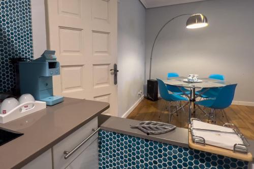 a kitchen with a table and blue chairs and a door at Apartamentos Santa Lucia in Cabezón de la Sal