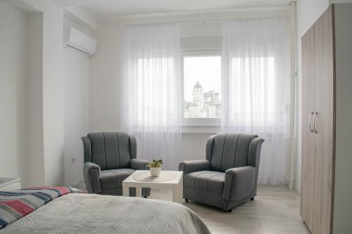 ein Schlafzimmer mit 2 Stühlen, einem Bett und einem Fenster in der Unterkunft Meli apartman in Smederevo