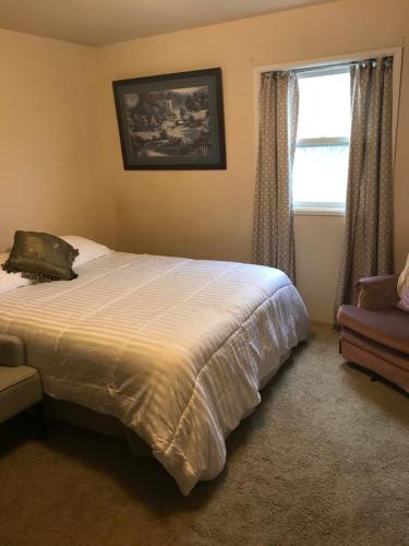 um quarto com uma cama, uma janela e uma cadeira em George's B&B em Lewiston