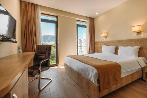 um quarto de hotel com uma cama, uma secretária e uma janela em Atrium Boutique Hotel em Tbilisi