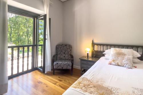 Un dormitorio con una cama y una silla y una ventana. en Apartamentos Santa Lucia, en Cabezón de la Sal
