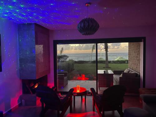 una sala de estar con luces moradas en el techo en OCEAN VIEW, Prestigia Plage des Nations en Sidi Bouqnadel