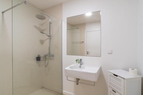 a white bathroom with a sink and a shower at Buzz Apartment in Jardim do Mar