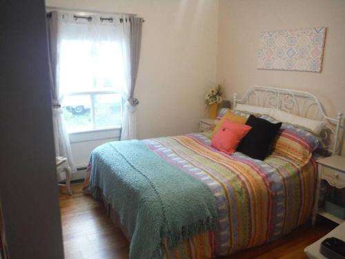 a bedroom with a bed with a colorful blanket and a window at Gîte Richmond Inn in Richmond