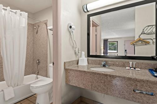a bathroom with a toilet and a sink and a mirror at Americas Best Value Inn Laurel in Laurel