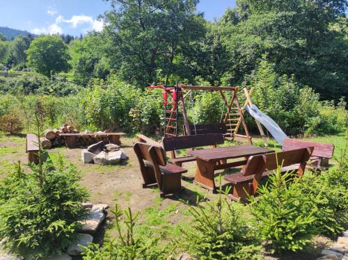 a garden with a picnic table and a swing at Drewniany Domek Daria i Tomek 2 domki na 8 osób in Stronie Śląskie