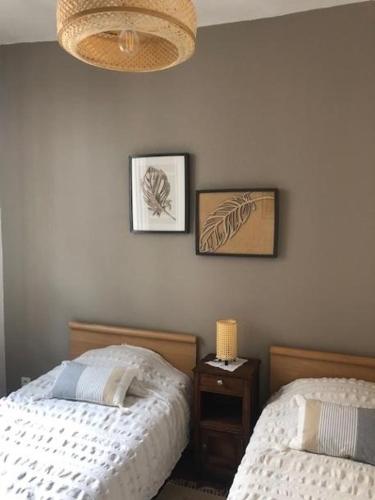 une chambre avec deux lits et deux tableaux au mur dans l'établissement Maison ICHABELENIA, à Salies-de-Béarn