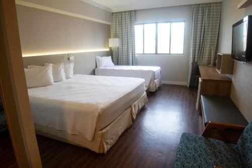 a hotel room with two beds and a television at Bourbon Santos Convention Hotel in Santos