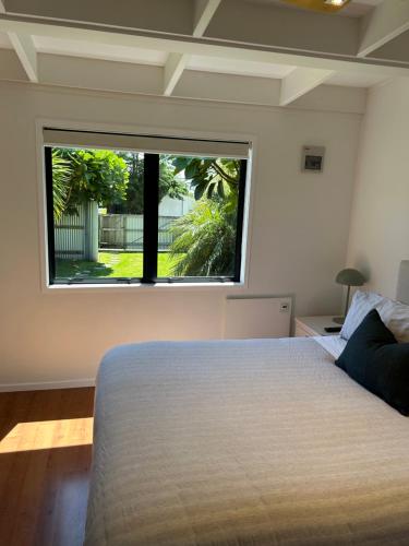 a bedroom with a bed and a large window at Evolve Bach in Whitianga