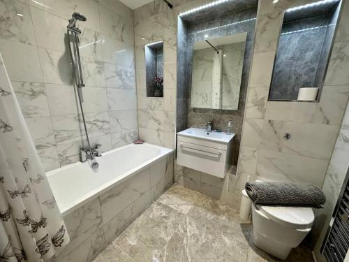 a bathroom with a tub and a toilet and a sink at Bourton House Windrush Lake in South Cerney