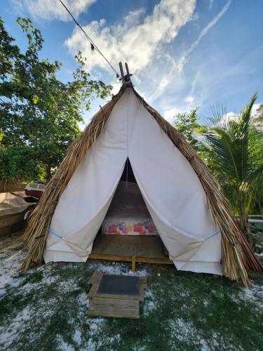 a white tent with a mattress in the grass at Saona lodge in Mano Juan