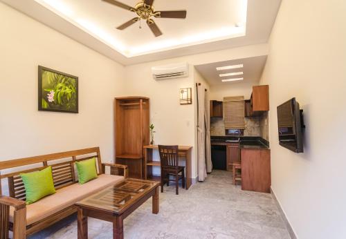 a living room with a couch and a kitchen at Villa Orchid Garden Riverside Hoi An in Hoi An