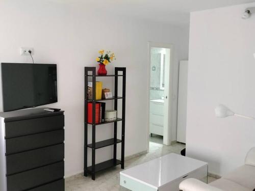 ein Wohnzimmer mit einem TV und einer schwarzen Kommode in der Unterkunft Apartamento La Doncella in Alcalá de Henares