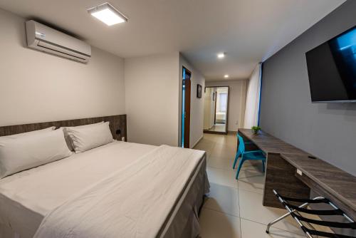 a bedroom with a bed and a desk and a television at Hotel Mais1 in Campina Grande