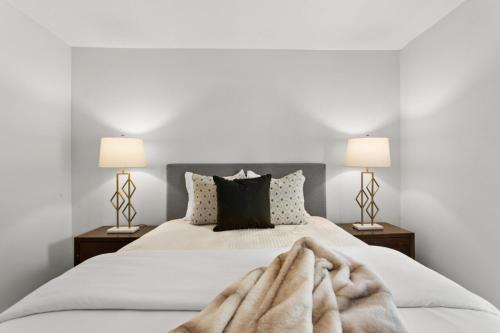 a white bedroom with a large bed with two lamps at UNIVERSITY SERENITY SUITES in Tampa