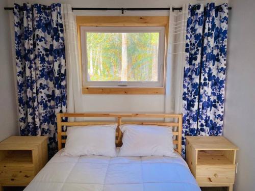 a bedroom with a bed and a window with curtains at Four Season Cottage with Wood Burning Sauna in Ompah