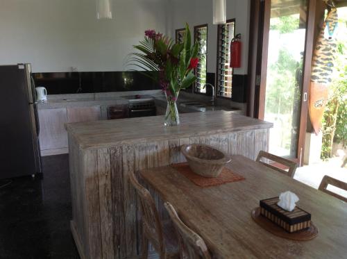 a kitchen with a wooden table with a vase of flowers on it at Villa Penyon in Nusa Lembongan