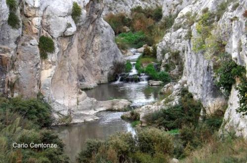 a river in a rocky canyon with a waterfall at Suite Vecchia Stalla in Gravina in Puglia
