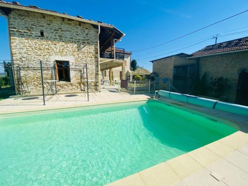 a swimming pool in front of a stone house at La Maison des Crêtes in Parnans
