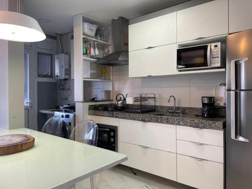 a kitchen with white cabinets and stainless steel appliances at Rossi Atlantida Apartamento in Xangri-lá